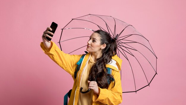 Mujer sonriente tomando un selfie mientras sostiene un paraguas