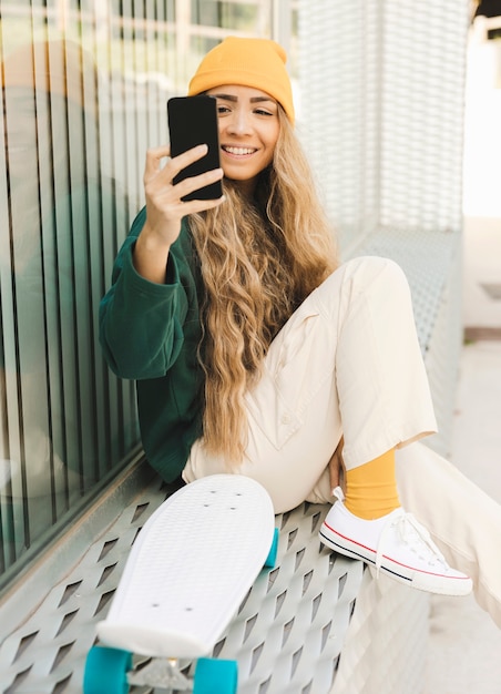 Mujer sonriente tomando selfie con patineta