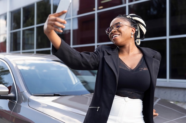 Mujer sonriente tomando un selfie con su coche nuevo