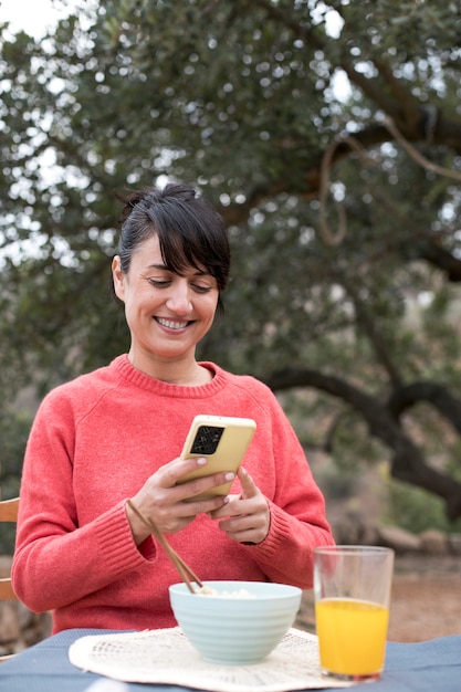 Mujer sonriente de tomas medianas tomando fotos de comida