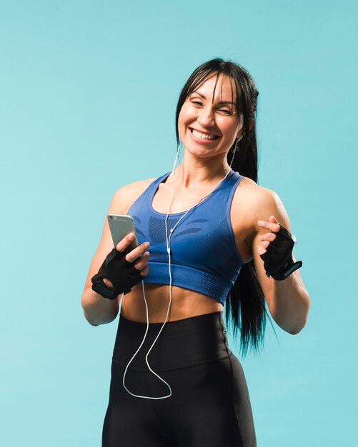 Mujer sonriente en traje de gimnasio disfrutando de la música en los auriculares