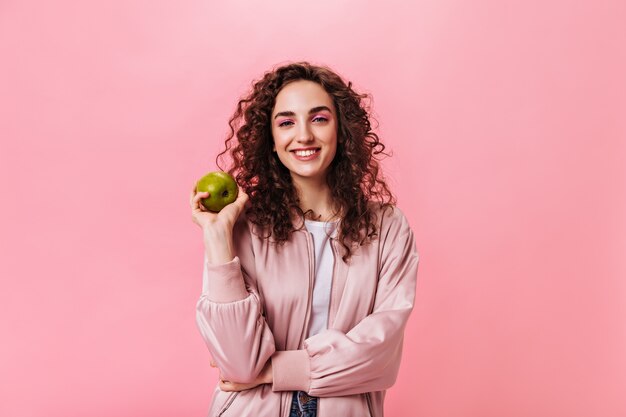 Mujer sonriente en traje rosa con manzana fresca