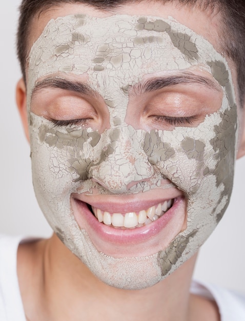 Foto gratuita mujer sonriente con tratamiento de barro en la cara