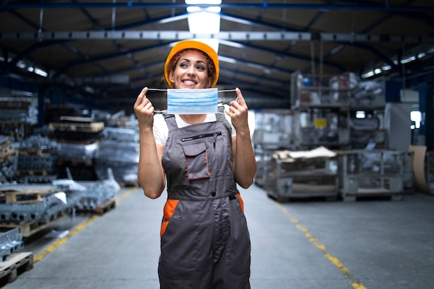 Foto gratuita mujer sonriente en uniforme y casco poniéndose mascarilla higiénica como prevención del virus corona