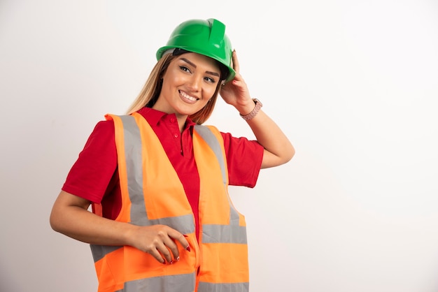 Mujer sonriente en uniforme protector y casco posando sobre fondo blanco.