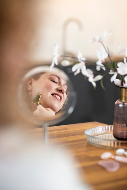 Mujer sonriente usando la herramienta gua sha