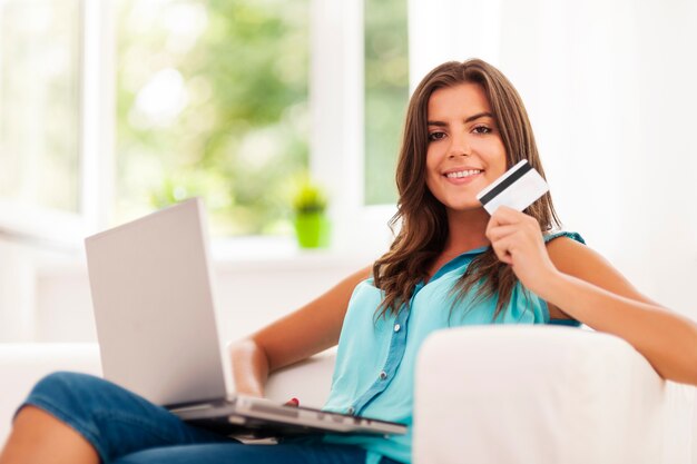 Mujer sonriente usando laptop y sosteniendo tarjeta de crédito