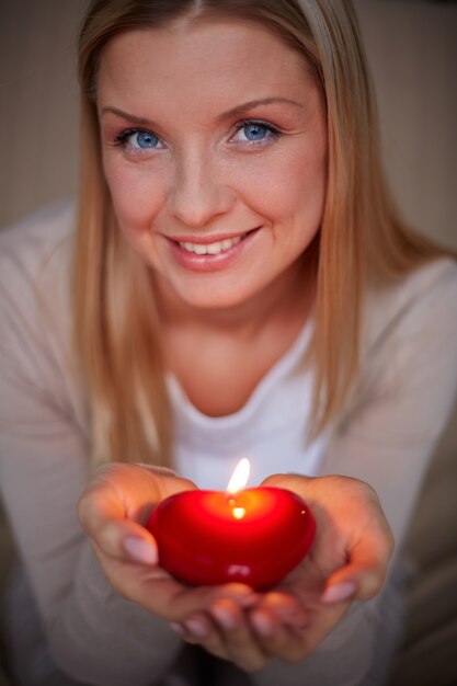 Mujer sonriente con una vela en forma de corazón