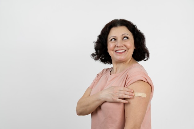 Mujer sonriente con vendaje en el brazo después de la vacunación