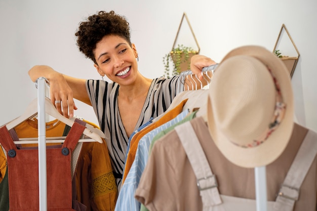 Foto gratuita mujer sonriente vendiendo ropa en línea plano medio