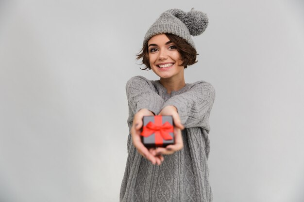 La mujer sonriente vestida con suéter le da un regalo.