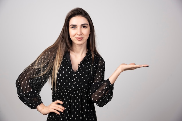 Mujer sonriente en vestido negro que muestra el espacio abierto.