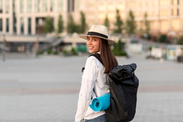 Mujer sonriente viajando sola con mochila