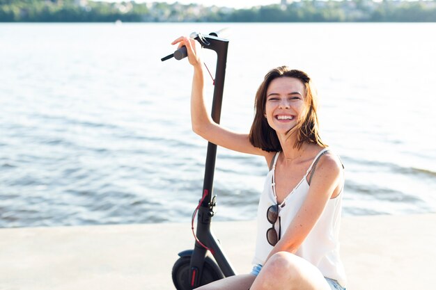 Mujer sonriente de la vista delantera que presenta en la vespa