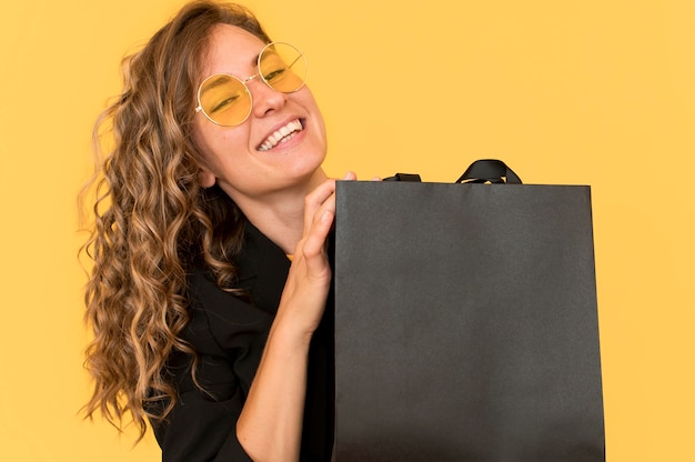 Mujer sonriente de vista frontal y bolso de compras negro