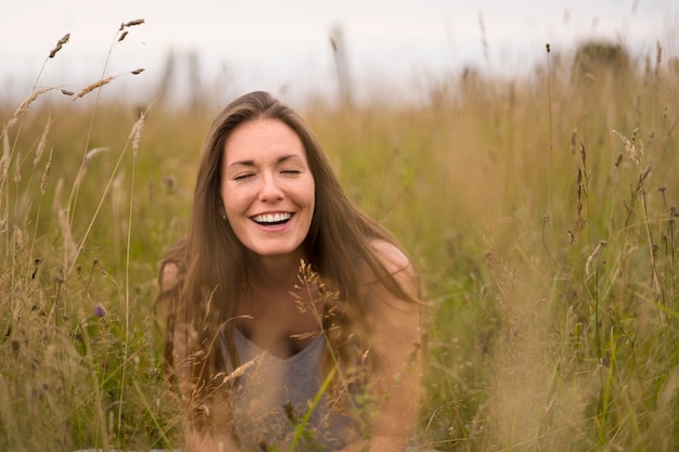 Mujer sonriente de vista frontal posando en la naturaleza