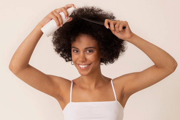 Mujer sonriente de vista frontal usando producto para el cabello