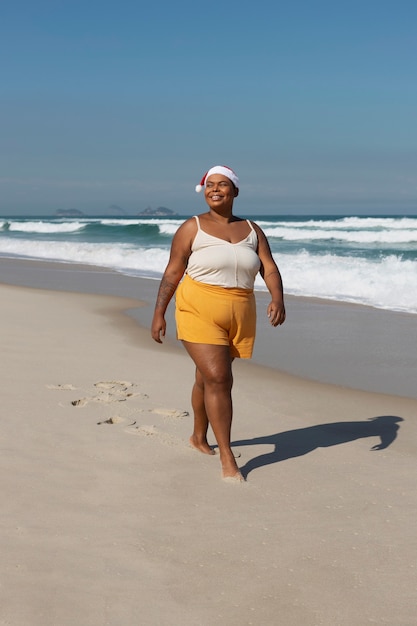 Mujer sonriente de vista lateral caminando en la playa