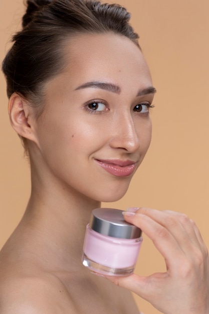 Mujer sonriente con vista lateral del contenedor de crema