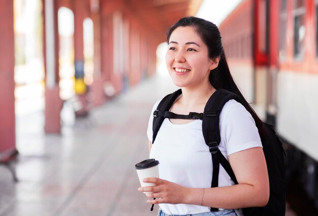 Mujer sonriente de vista lateral en la estación de tren