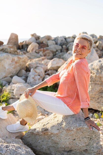 Mujer sonriente de vista lateral posando sobre rocas