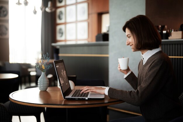 Mujer sonriente de vista lateral que trabaja con la computadora portátil