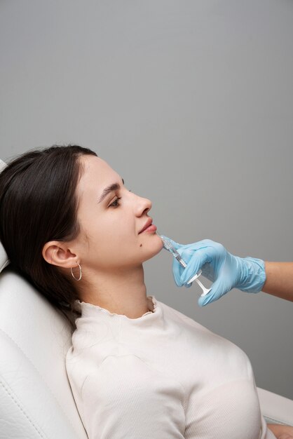 Mujer sonriente de vista lateral recibiendo rellenos de labios