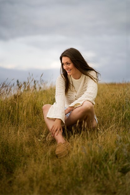 Mujer sonriente de vista lateral sentada en la hierba