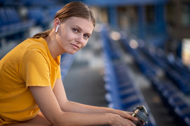 Mujer sonriente de vista lateral sentada en la tribuna