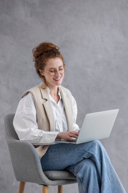 Mujer sonriente de vista lateral trabajando en la computadora portátil