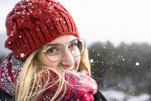 Mujer sonriente vistiendo gorro de lana y bufanda en un día frío de invierno.