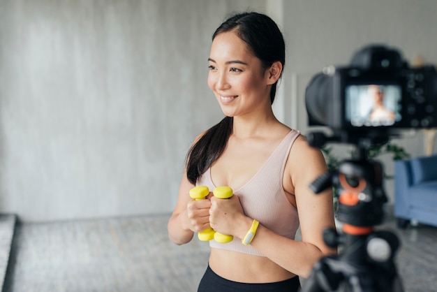 Foto gratuita mujer sonriente vlogging en ropa deportiva en casa