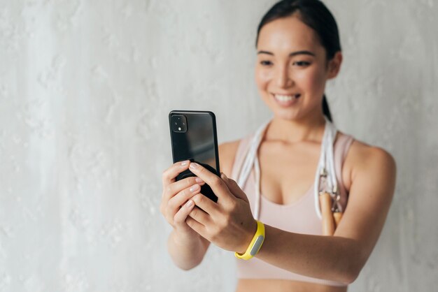 Mujer sonriente vlogging en ropa deportiva con su teléfono