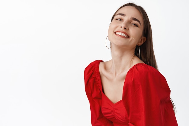 mujer con sonrisa blanca despreocupada, disfrutando de una cita romántica, noche perfecta saliendo, vestida con un vestido rojo, bailando y luciendo alegre en blanco.