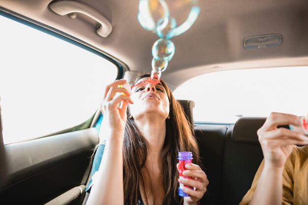 Mujer soplando burbujas en el coche