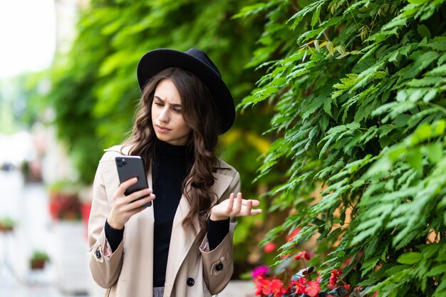 Mujer sorprendida al encontrar noticias sorprendentes en un teléfono inteligente en la calle