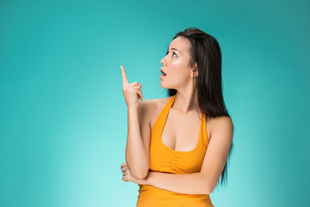 Mujer sorprendida apuntando hacia arriba