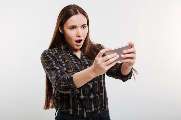 Mujer sorprendida en camisa jugando en el teléfono