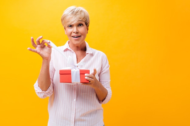 Mujer sorprendida en camisa rosa tiene caja de regalo