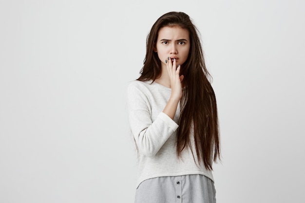 Mujer sorprendida en camisa suelta con expresión sorprendida, descubre noticias inesperadas, no puede creer en las palabras que le dicen, dice: ¿es realmente así? la mujer emocional cierra la boca con la mano emocionada