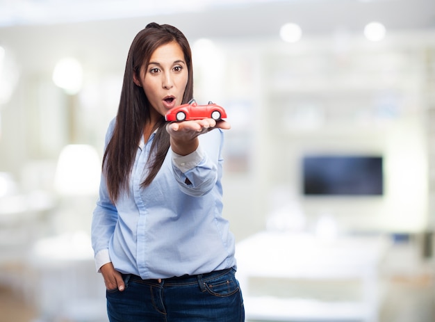 Mujer sorprendida con un coche de juguete
