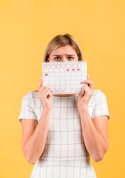 Mujer sorprendida cubriendo su rostro con calendario de época