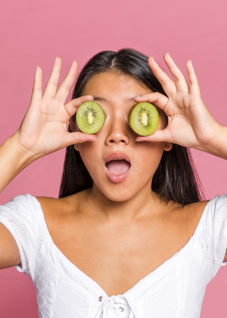 Foto gratuita mujer sorprendida cubriendo sus ojos con kiwi