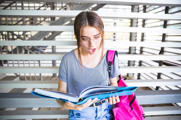Mujer sorprendida en gafas leyendo libros de texto