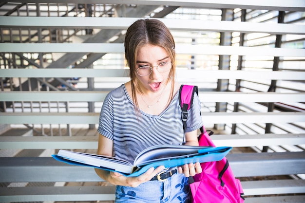 Mujer sorprendida en gafas leyendo libros de texto