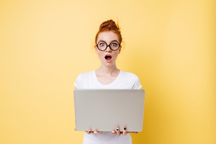 Foto gratuito mujer sorprendida con gafas sosteniendo una computadora portátil