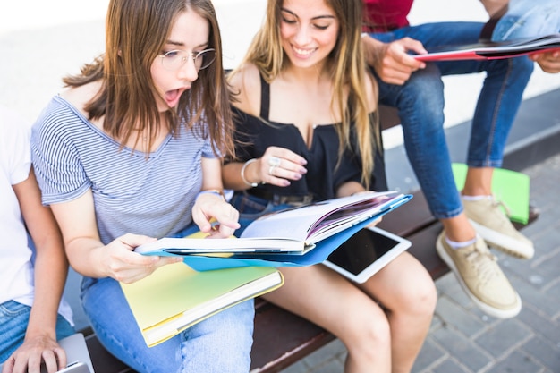 Foto gratuita mujer sorprendida leyendo libros de texto con un amigo