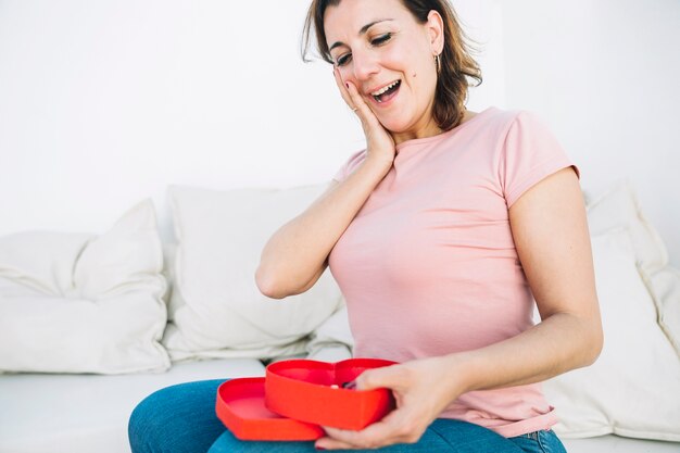 Mujer sorprendida mirando caja en forma de corazón