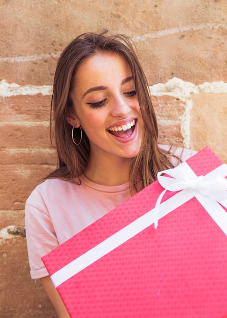 Mujer sorprendida mirando caja de regalo roja