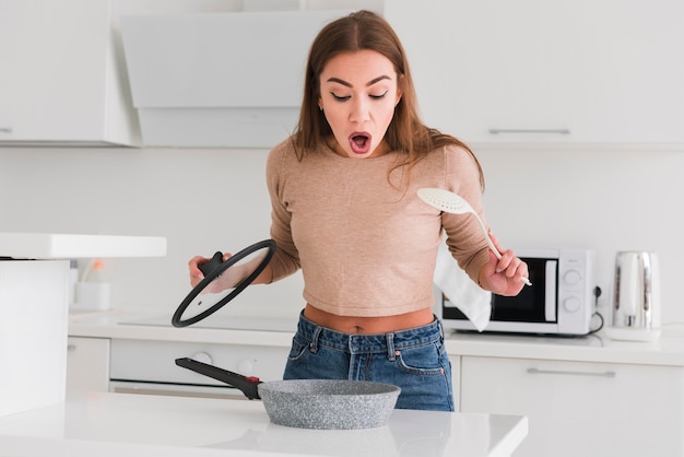 Mujer sorprendida mirando en una sartén